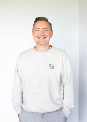 Dr Christoph in a casual sweater bearing the 1X logo