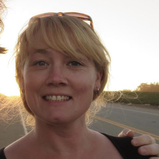 AmyJune stands by a road with the sun setting in the background