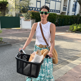 Pamela Barone rides her bike on a quiet street, with bread in the front basket