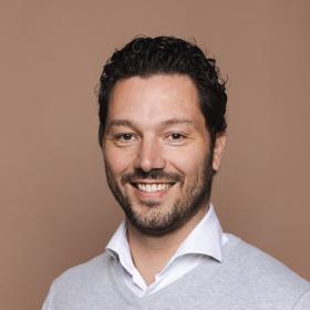 Jean-Paul Vosmeer smiling, wearing a shirt and sweater 